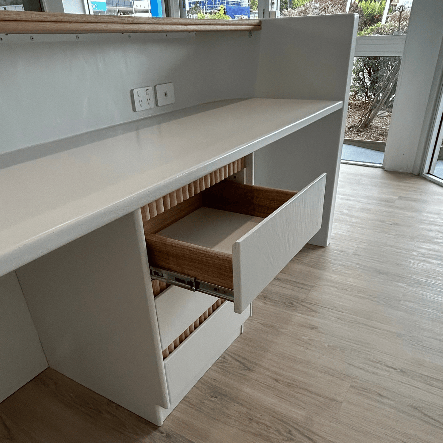 White desk with a drawer open on a wooden floor