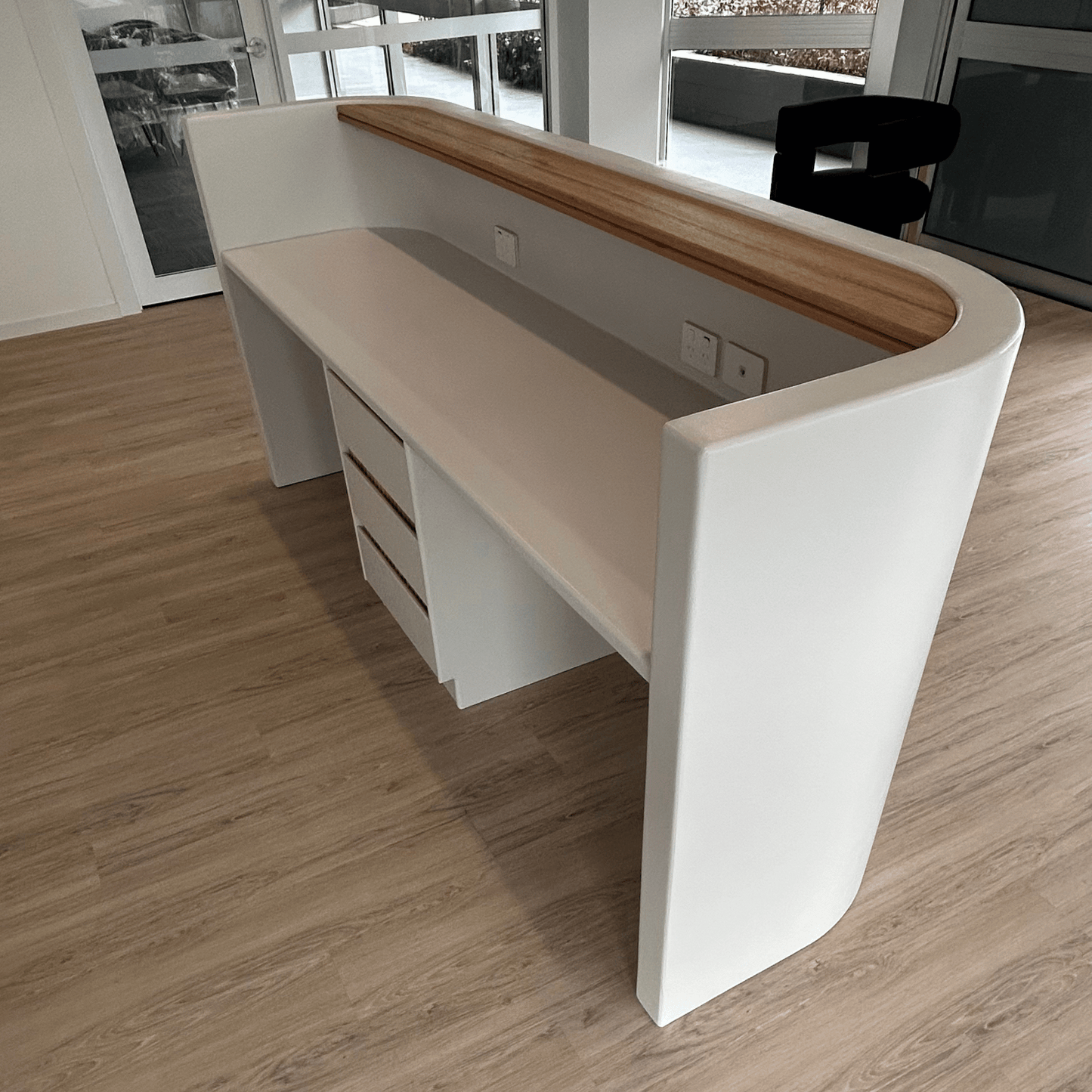 Modern white reception desk with wooden top in a room setting