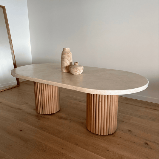 Beige oval table with ribbed cylindrical legs on a wooden floor.