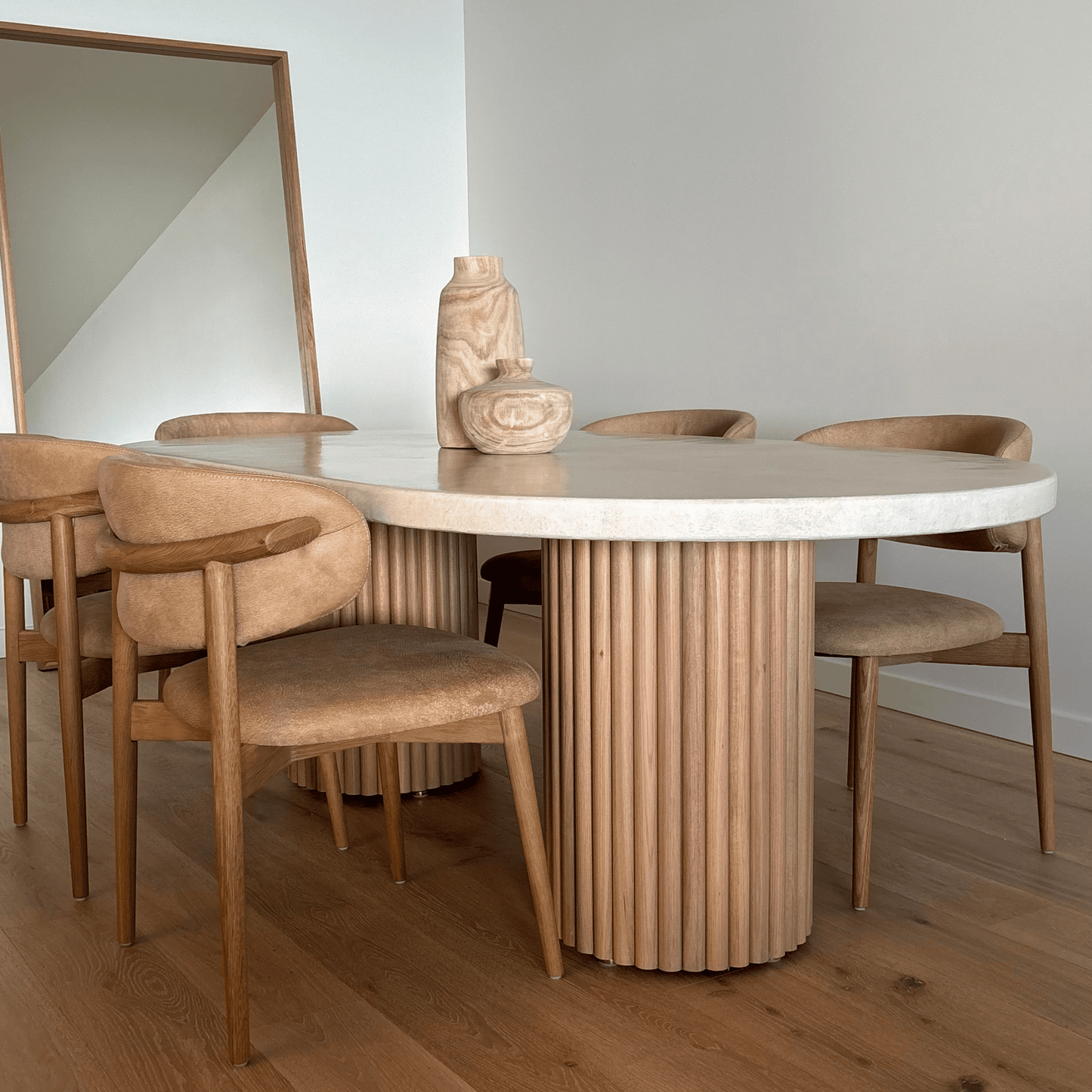 Dining area with a round wooden table and chairs in a minimalistic setting.
