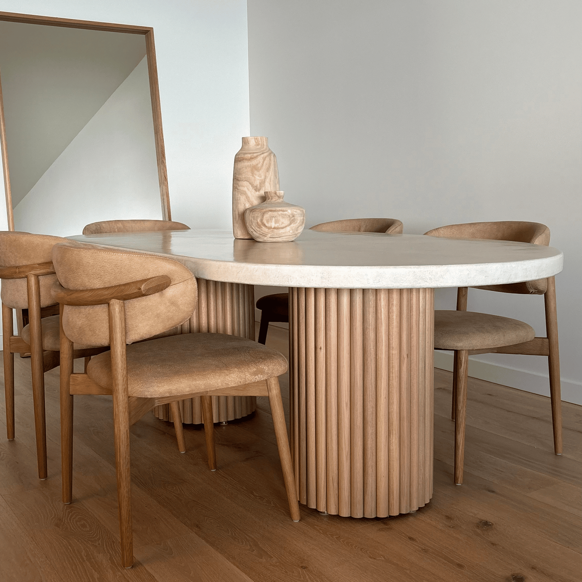Dining area with a round wooden table and chairs in a minimalistic setting.